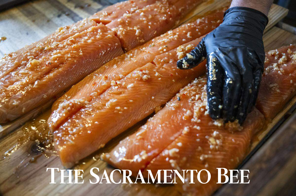 marinated salmon being cut on a wood plank