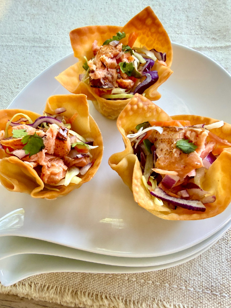 Close-up of a Crispy Salmon Cup filled with California King Salmon, cabbage slaw, red onion, and cilantro in a crispy wonton shell.
