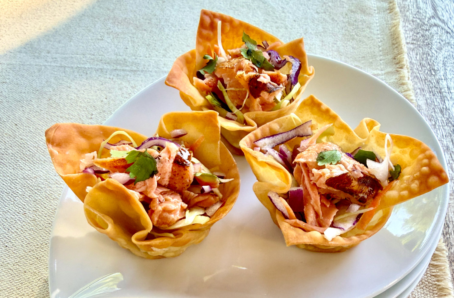 Crispy Salmon Cups made with California King Salmon, colorful slaw, and wonton wrappers served on a white plate.